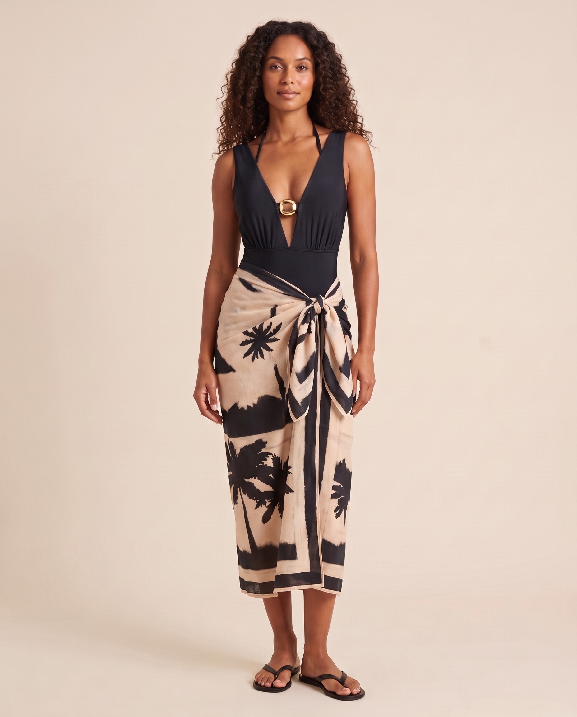 Studio view of the complete black swimsuit and halter top worn with the beige palm-print sarong.