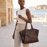 Ayla coffee-brown tote bag carried on a coastal promenade