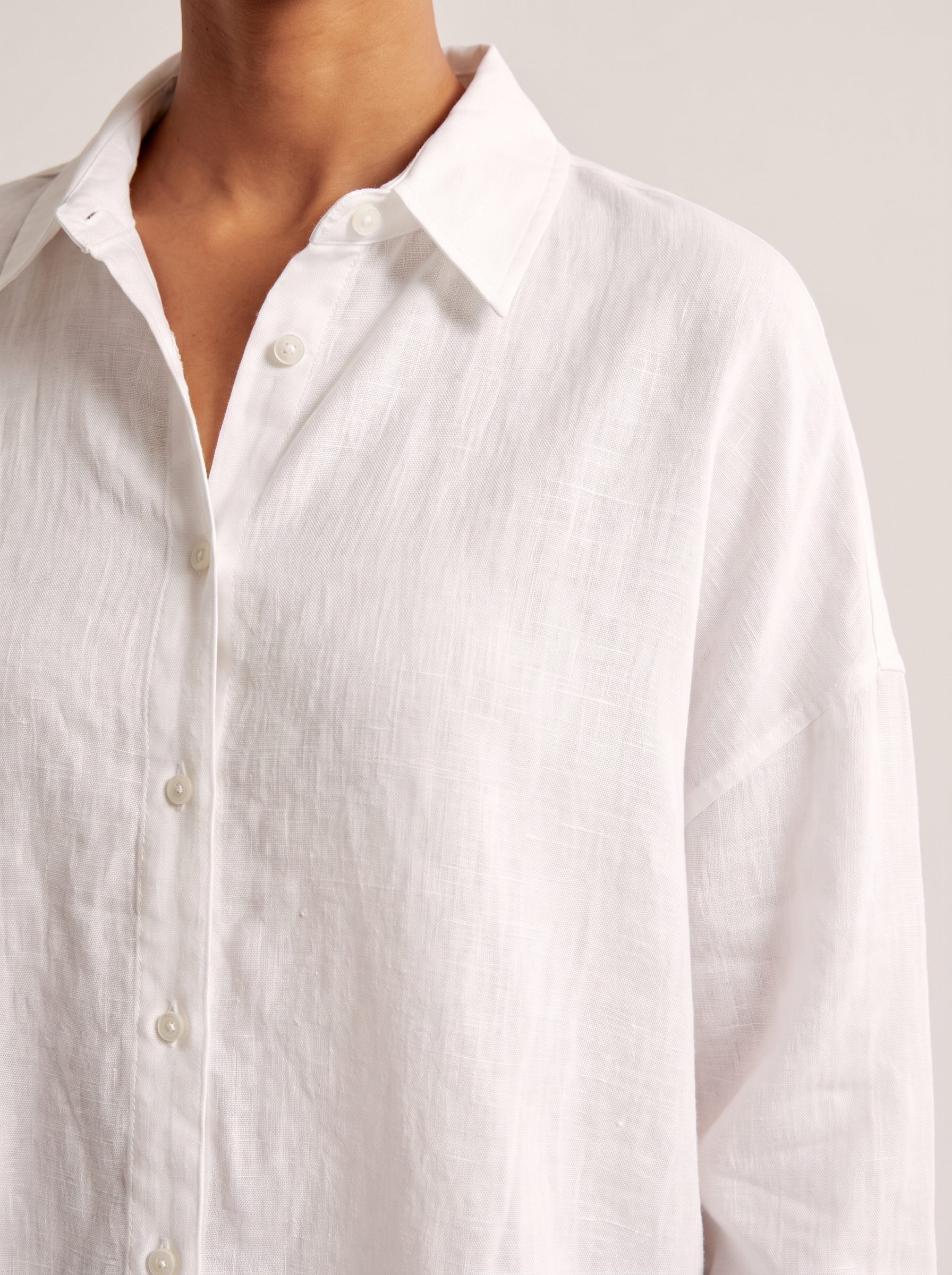 Oversized Linen Shirt with Button Front — tight editorial product detail showing the fabric texture, stitching, neckline and construction